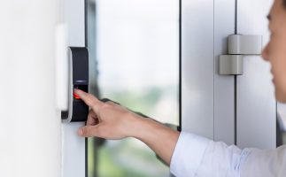 Asian businessman's hand using fingerprint sensor door lock, modern doorbell with video camera